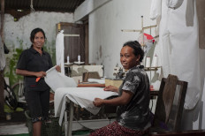 Sri Mulyani, 45, and Sri Suparmi, 31, sew hazmat suits at their home in Wedomartani village, Sleman, on April 1. The two help a community of disabled tailors to finish the suits, which are urgently needed by a local hospital. JP/ Arnold Simanjuntak
