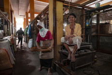 Rubiyem (right), a 70-year-old porter, sits at the corner of Bringharjo Market on April 6. She usually gets a daily income of Rp. 20,000 (US$ 1.26) for carrying produce with a total weight of 50 kilograms. She works seven days a week and does not have a mask to protect herself from COVID-19. 
JP/Arnold Simanjuntak
