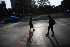 Two people observe minimum safe distance as they pass each other on April 16, 2020 along the otherwise deserted sidewalk of Jl. Sudirman in Central Jakarta. 