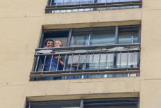 Australian residents wave from a hotel balcony in Adelaide where they will go through a mandatory 14-day quarantine after returning on a repatriation flight carrying over 300 passengers who were stranded abroad due to the COVID-19 coronavirus outbreak on April 21, 2020. 