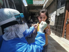 A member of a medical team that works with mobile coronavirus disease (COVID-19) testing units wears protective gear as he takes a swab from a child to track new cases of COVID-19, in Najaf, Iraq April 21,2020. 