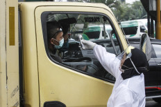 A worker from the Bandung Health Agency checks the temperature of a truck driver on April 22 at Jl. Pasteur in Bandung, West Java.