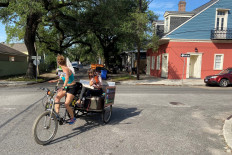 Pedicab operator Sarah Grant and French Quarter street violinist Anna Roznowska cycle in New Orleans, Louisiana, United States on April 21, 2020. 