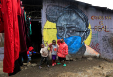 Children pose in front of a graffiti made by artists of the Mathare Roots's youth group, advocating against the spread of the coronavirus disease (COVID-19), at the Mathare Valley slum, in Nairobi, Kenya, on April 19, 2020. 