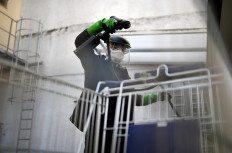 Working student Leon Rottmann coats a shopping trolley for disinfection at the mechanic's workshop of the Startup UVIS UV-Innovative Solutions in Cologne, western Germany, on April 22, 2020, amid the novel coronavirus COVID-19 pandemic. The Startup UVIS UV-Innovative Solutions of Katharina Obladen and Tanja Nickel developed a chemical-free disinfection for the handrails of escalators and surfaces. A module continuously irradiates them with UV light as they pass through. The rays in the UV-C spectrum kill bacteria, moulds and viruses.