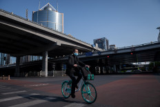 A man wearing a facemask amid concerns over the COVID-19 coronavirus drives a shared bicycle on a street in Beijing on April 23, 2020. 