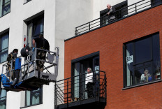 Relatives stand on an aerial platform installed near the facade of Belgian care home Le Cinquantenaire Orpea, allowing people to be in touch with their loved ones while inside their room, amid the outbreak of the coronavirus disease (COVID-19), in Brussels, Belgium, on April 27, 2020. 