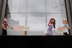 Children's dolls and signs reading 'Stay Home' and 'Working on a Vaccine' stand in a window planter outside a home amid the coronavirus disease (COVID-19) outbreak in Boston, Massachusetts, US, April 28, 2020.   