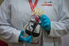 An official from the Indonesian Red Cross (PMI) shows a blood bag from a donor on April 30, 2020, at the PMI's blood transfusion unit in Central Jakarta.