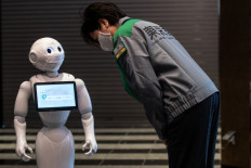 Tokyo Governor Yuriko Koike (right) looks at a greeting robot called 