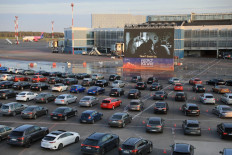 People sitting in their cars watch a movie at the Autokino drive-in cinema on an airfield of the airport in Vilnius on April 29, 2020. 