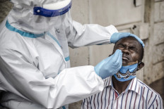 A man reacts while a health worker wearing personal protective equipment (PPE) uses a nasal swab to collect a sample during the COVID-19 coronavirus mass testing exercise inducted by Kenya’s Ministry of Health in the Kawangware slums of Nairobi, Kenya on May 1, 2020. 