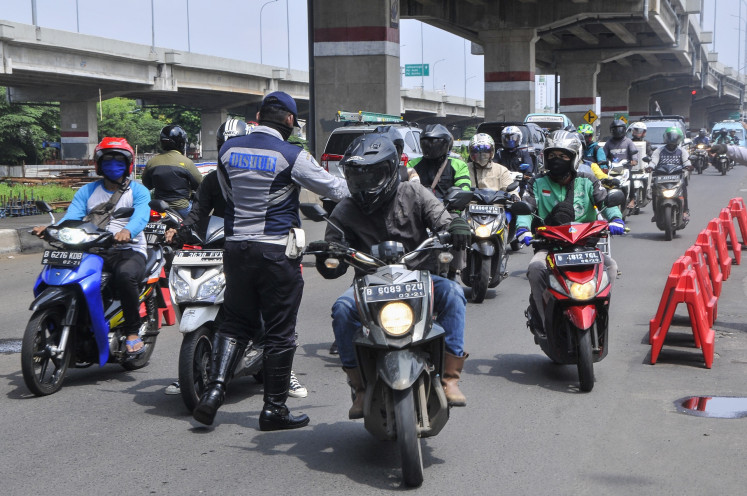 An official of the West Java Transportation Agency holds motorists in Kalimalang, Bekasi, West Java on Monday, April 27, 2020. Authorities open checkpoints in Jakarta borders to hold homecoming travelers from leaving the city amid the government's mudik (exodus) ban to curb the COVID-19's spread.