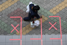 A security guard carrying bags of takeaway food walks past safe distance markers, as a protective measure against the spread of the COVID-19 novel coronavirus, in Singapore on May 2, 2020. 