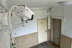 A worker adjusts a surveillance camera outside the home of a journalist placed under quarantine after he had visited Wuhan, in Beijing on May 3, 2020. 