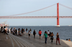 People walk past 25th April Bridge along the Tagus river, as the spread of the COVID-19 continues, in Lisbon, Portugal, on May 3, 2020.On Wednesday, lockdown restrictions were reimposed on 19 neighborhoods across the northern periphery of Lisbon where COVID-19 outbreaks persist. The restrictions concern some 700,000 people and will remain in place for at least two weeks.