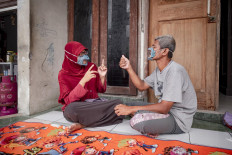 Dwi and her husband Elfiandi wear clear masks while chatting in front of their home. JP/Arnold Simanjuntak
