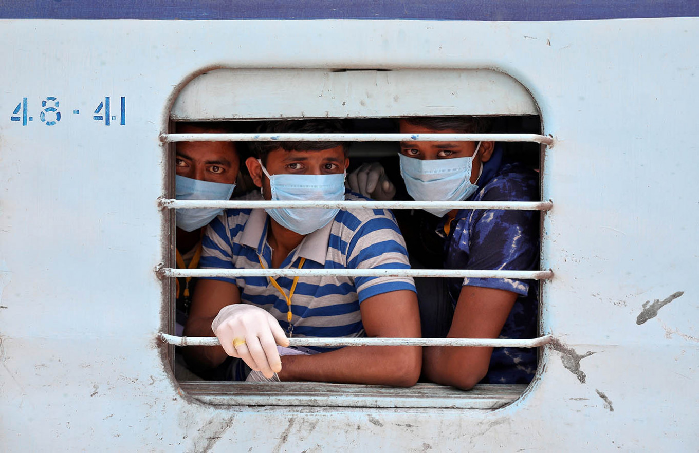 Migrant workers, who were stranded in the western state of Rajasthan due to a lockdown imposed by the government to prevent the spread of COVID-19, wear protective masks as they look out from a window of a train upon their arrival in their home state of eastern West Bengal, at a railway station on the outskirts of Kolkata, India, May 5, 2020. India announced a limited reopening of its giant rail network beginning on Tuesday after a nearly seven-week lockdown, despite also reporting its biggest single-day jump in coronavirus cases.