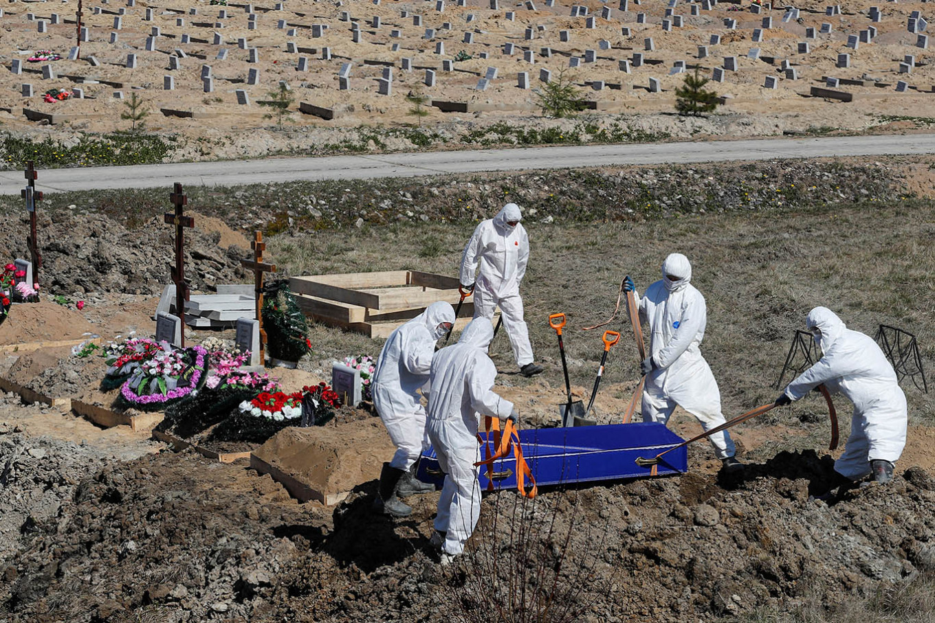 Grave diggers wearing personal protective equipment (PPE) lower a coffin while burying a COVID-19 victim in the special purpose section of a graveyard on the outskirts of Saint Petersburg, Russia May 5, 2020. Russia on Friday reported its highest ever daily coronavirus death toll of 150, even though the number of new infections fell below 9,000 for the third day in a row.