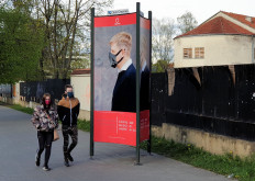 People walk on a street next to a billboard, a part of a 'Mask Fashion Week' during the coronavirus disease (COVID-19) outbreak in Vilnius, Lithuania, on May 5, 2020. 