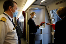 Air France flight crew members wearing protective face masks distribute face masks to passengers at Paris Charles de Gaulle airport in Roissy-en-France during the outbreak of the coronavirus disease (COVID-19) in France, May 6, 2020. 