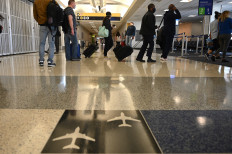 People wearing a masks due to the COVID-19 pandemic wait to board a plane in the George Bush Intercontinental Airport on May 6, 2020 in Houston Texas.
