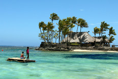 In this file photo taken on November 11, 2003 Melanesian children float on a bamboo pontoon by Wicked Walu Island on the resort-studded Coral Coast of Fiji. 