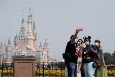 Visitors wearing protective face masks pose for a picture at Shanghai Disney Resort as the Shanghai Disneyland theme park reopens following a shutdown due to the coronavirus disease (COVID-19) outbreak, in Shanghai, China, on May 11, 2020. 