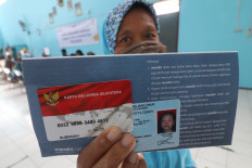 A resident shows a social aid card for staple food assistance at Campurejo subdistrict in Kediri city, East Java on May 12. The aid comes in the form of food parcels provided by the government for those affected by the COVID-19 pandemic,