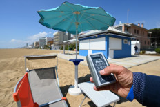 A view taken on May 12, 2020 shows a man showing a sunshade remote controller at a private beach in Jesolo, near Venice, northeastern Italy, during a demonstration of hygiene and safety precautions for customers against the spread of COVID-19, during the country's lockdown aimed at curbing the spread of the COVID-19 infection, caused by the novel coronavirus. 
