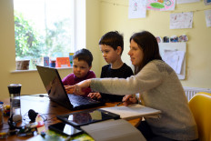 Leo (C), aged 6, and Espen, aged 3, are assisted by their mother Moira as they navigate online learning resources provided by their infant school in the village of Marsden, near Huddersfield, northern England on March 23, 2020 on the first school day since the nationwide closure of almost all schools except for the children of 'key workers', amidst the novel coronavirus COVID-19 pandemic. 