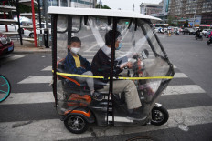 A man and a boy wear face masks as a precaution against the COVID-19 coronavirus as they wait to cross a road in Beijing on May 15, 2020.
