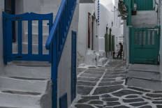 A worker stands outside a store in a narrow alleys in the Greek Cycladic island of Mykonos, on May 12, 2020. 