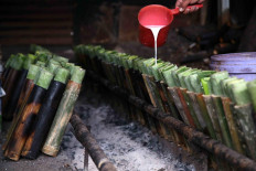 Sukri pours coconut milk into a line of bamboo tubes. JP/P.J. Leo