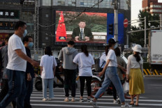A news program shows Chinese President Xi Jinping speaking via video link to the World Health Assembly, on a giant screen beside a street in Beijing on May 18, 2020. - China supports a 