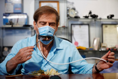 Meir Gitelis, co-developer of an Israeli company, eats while wearing a mask fitted with a mechanical mouth that opens to enable diners to eat without taking it off, as the coronavirus disease (COVID-19) restrictions ease, at Avtipus Patents and Inventions lab in Or Yehuda, Israel May 18, 2020. 