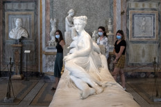 Visitors wearing a face mask view 'Paolina Borghese Bonaparte as Venus Victrix', a 1805-1808 marble sculpture by Antonio Canova at the Galleria Borghese museum in Rome on May 19, 2020, as it reopens while the country's lockdown is easing after over two months, aimed at curbing the spread of the COVID-19 infection, caused by the novel coronavirus.
