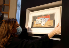 Raffle organizer Peri Cochin, wearing a protective face mask, poses with the painting 'Nature Morte, 1921' by Spanish painter Pablo Picasso after the charity raffle official draw to designate the winner of the Picasso oil painting for 100 euros at Christie's auction house in Paris, on May 20, 2020. 