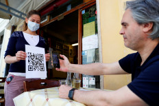 A waiter holds a placard showing a barcode that customers scan on their phones to view the restaurant menu, to avoid using paper menus that are touched by many customers, as Italy eases some of the lockdown measures put in place following the coronavirus disease (COVID-19) outbreak, in Rome, Italy, on May 20, 2020. 