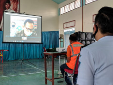 Busted: Bangladeshi national MilonHossain (in orange vest), the suspect of an immigration fraud case, listens to the charges against him during a virtual trial hearing at the Blitar District Court in Blitar, East Java.