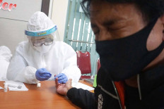 A man closes his eyes as an officer takes his blood sample at the Malang City Health Office in East Java on May 18. The city administration aims to provide rapid tests for those who face a high risk of contracting COVID-19. JP/Nedi Putra A.W.