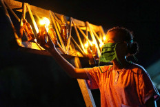 Light up the dark: A girl lights up an oil lamp during the tumbilotohe celebration in Gorontalo, Gorontalo on Wednesday. The celebration is a local’s tradition celebrated a couple of days before Idul Fitri. Antara/Adiwinata Solihin
