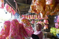 Still colorful: A vendor arranges a display of brightly colored snacks as she waits for customers on Wednesday at her stall on the North Coast Highway (Pantura) in Karawang, West Java. The COVID-19 pandemic has affected the revenue of Pantura snack stalls, which are usually very busy during Idul Fitri. Antara/Nova Wahyudi
