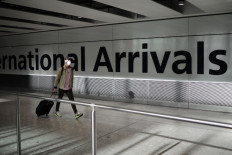 A passenger wearing a face mask as a precaution against the novel coronavirus arrives at Heathrow airport, west London, on May 22, 2020.The British government will effectively ditch its air bridge plans and simply end the coronavirus quarantine rules for those arriving from 75 countries so that people can go on holiday, The Daily Telegraph reported.