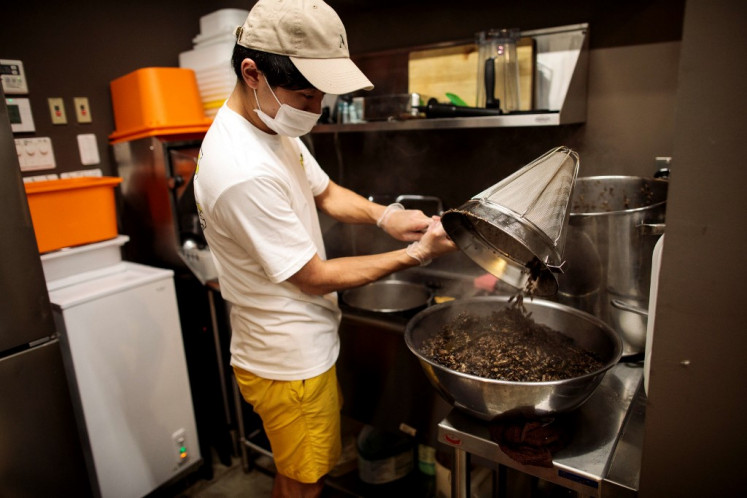In this picture taken on May 13, 2020 Yuta Shinohara throws away boiled crickets after straining the broth, used as an ingredient as part of cricket ramen home-cooking kits, at a kitchen in Tokyo. In a steamy Tokyo kitchen, a roasted scent wafts through the air as Yuto Shinohara prepares soup stock for ramen, derived not from pork or chicken, but crickets. Shinohara and his team had planned to open an insect cuisine restaurant named Antcicada in downtown Tokyo in April, but were forced to put it on hold because of the coronavirus pandemic. Instead, they have designed a pack of cricket ramen that can be cooked at home, and have sold 600 sets online as of mid-May.