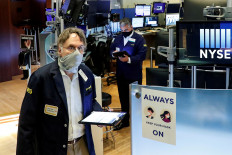 Traders wearing masks work, on the first day of in person trading since the closure during the outbreak of the coronavirus disease (COVID-19) on the floor at the New York Stock Exchange (NYSE) in New York, US, May 26, 2020. 