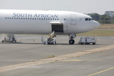 Workers wearing protective suit approach a South African Airways Airbus A340-600 plane on March 14, 2020 as it arrives in Polokwane, in Limpopo province, carrying South African citizens who have been repatriated from Wuhan, China, where they were working when the novel coronavirus (COVID-19) erupted. 