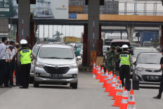 Police and military personnel check each vehicle seeking to enter Jakarta at the Cikupa tollgate in Tangerang on Wednesday. Drivers who fail to present an Exit and Entry Permit (SIKM) are forced to turn around to minimize the spread of Covid-19 in the city.