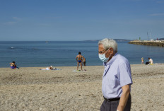 A man wearing a face mask walks along the Portixol beach in Palma de Mallorca on May 25, 2020, on the first day after beaches reopened in parts of the country after months-long closures. 