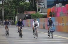 People wearing masks ride bicycles while keeping social distance on Jl. Jenderal Sudirman in Jakarta on Sunday. The government and businesses are gearing up to gradually reopen the economy under health protocols to establish a so-called 'new normal' amid the continued rise of confirmed COVID-19 cases in Indonesia.